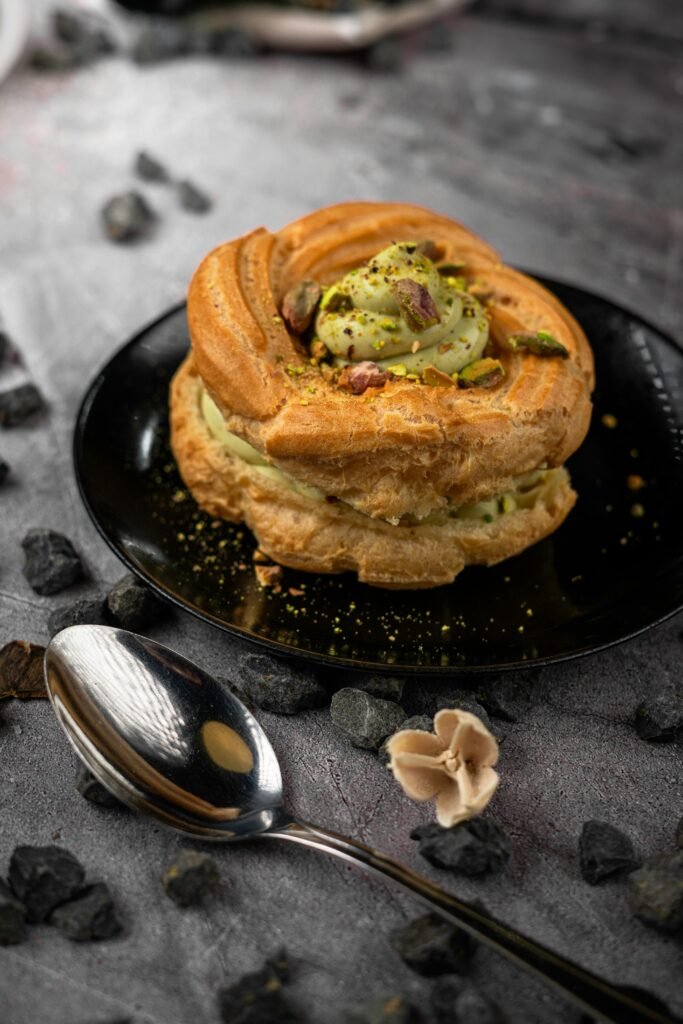 ARFID (zaburzenie unikająco–ograniczającego przyjmowania pokarmów) u osób z ASD i ADHD — jak odróżnić od „niejadkowania” i co robić w praktyce Close-up of a beautiful pistachio cream pastry served elegantly on a black plate, surrounded by decorative elements.